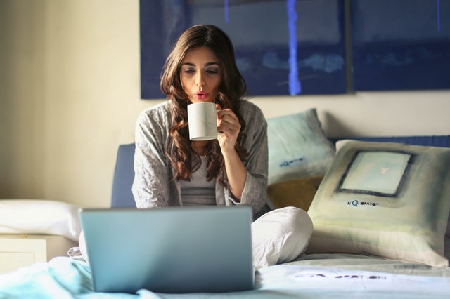 Woman looking at computer sipping coffee